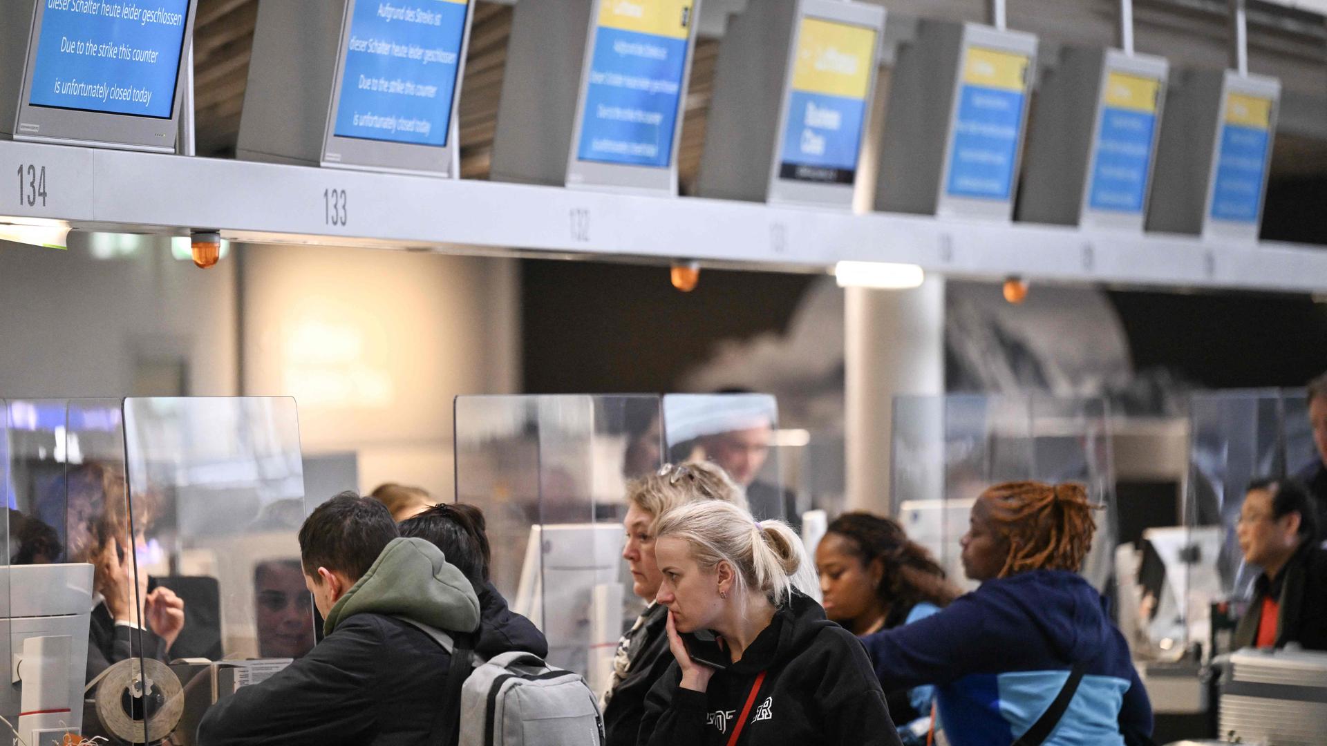 Passengers stand next to information boards announcing the booths are closed at German airline Lufthansa during a strike action by ground crews, services staff and security personnel, at Frankfurt's International Airport.