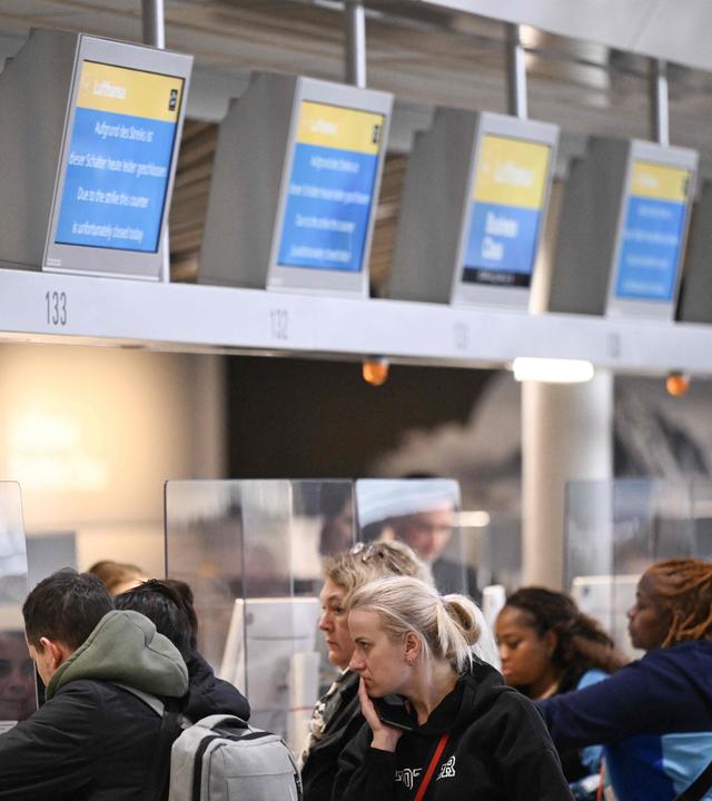 Passengers stand next to information boards announcing the booths are closed at German airline Lufthansa during a strike action by ground crews, services staff and security personnel, at Frankfurt's International Airport.
