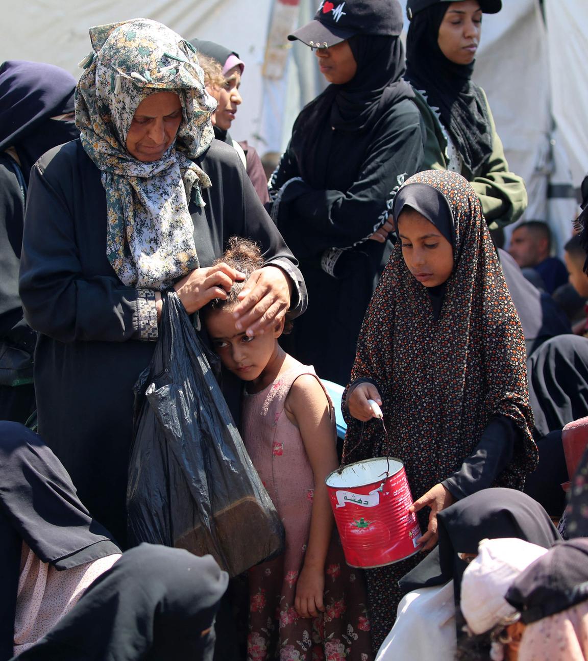 Archiv: Eine Frau streichelt den Kopf eines Kindes, während Palästinenser am 19. Juli 2025 an einer Lebensmittelausgabestelle im Flüchtlingslager Nuseirat im zentralen Gazastreifen warten. 