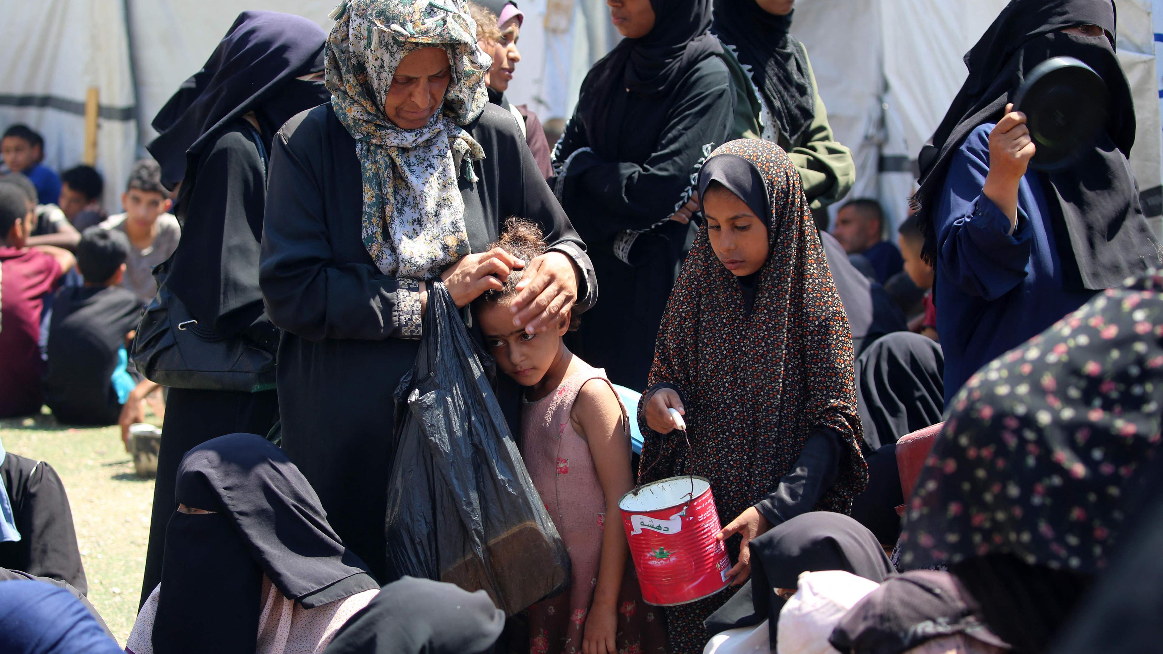 Archiv: Eine Frau streichelt den Kopf eines Kindes, während Palästinenser am 19. Juli 2025 an einer Lebensmittelausgabestelle im Flüchtlingslager Nuseirat im zentralen Gazastreifen warten. 