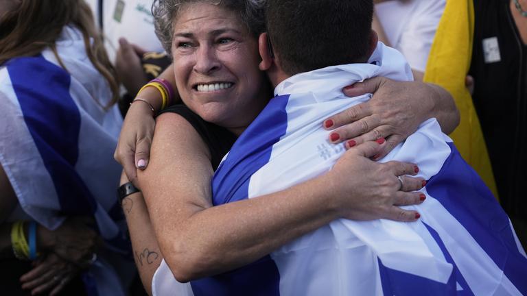 Israelis umarmen sich während sie auf die Freilassung der Geiseln auf dem Platz der Geiseln in Tel Aviv am 13.10.2025 warten.