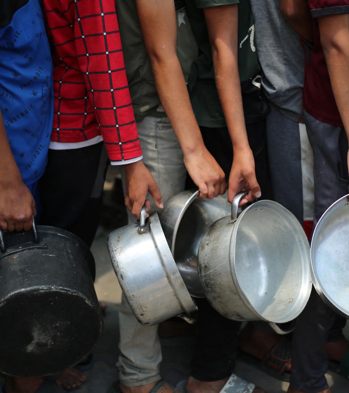 Palästinensische Jungen stehen mit leeren Töpfen in einer Schlange vor einer Essensausgabestelle im Gazastreifen, am 4. Juni 2025. 
