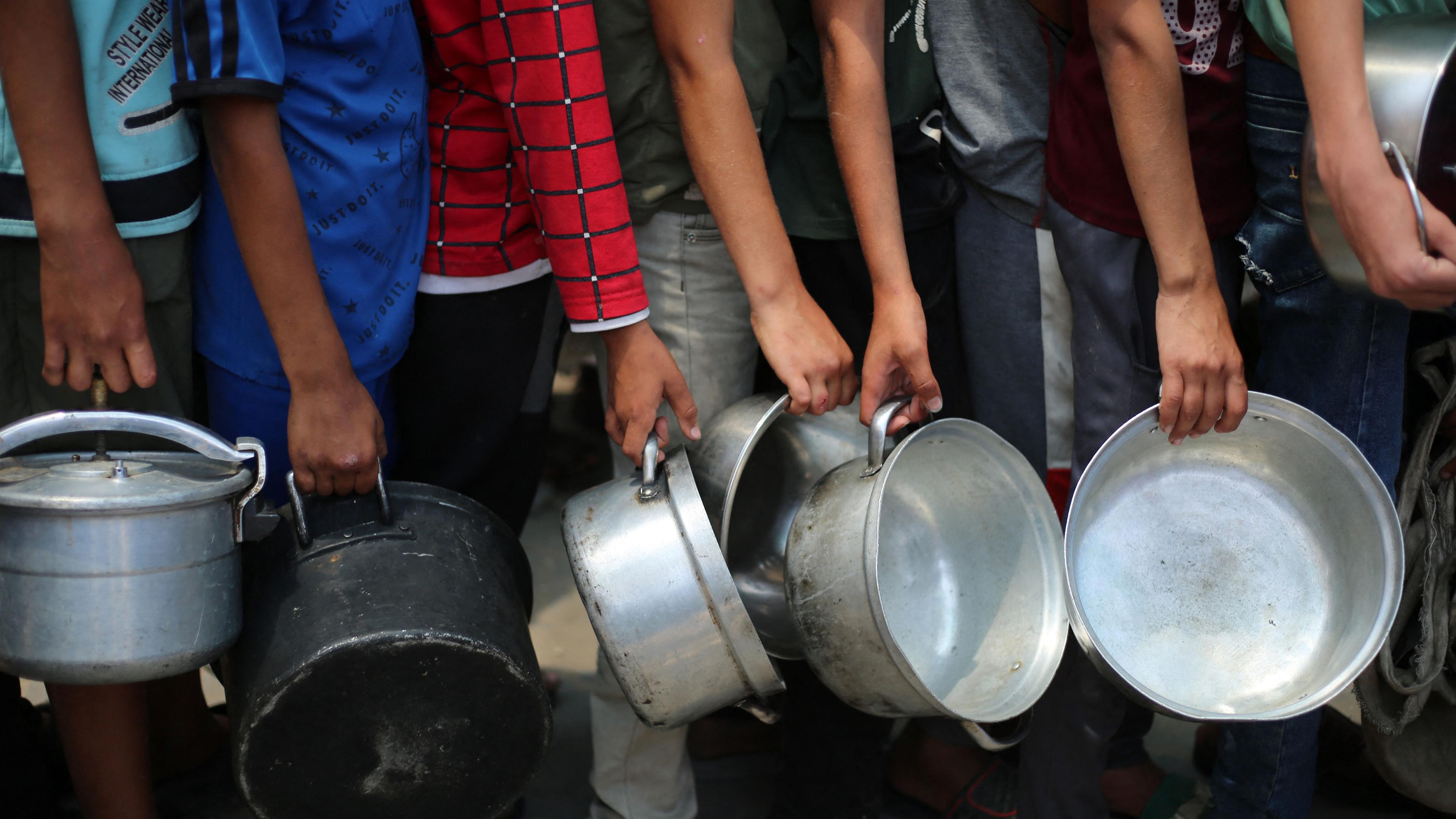 Palästinensische Jungen stehen mit leeren Töpfen in einer Schlange vor einer Essensausgabestelle im Gazastreifen, am 4. Juni 2025. 