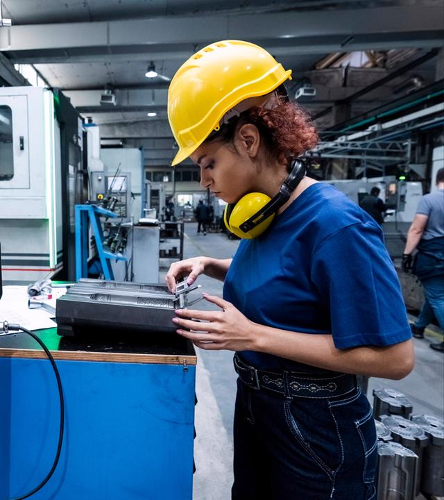 Wartungstechnikerin beim Einsatz von Robotik in einer modernen Fabrik 