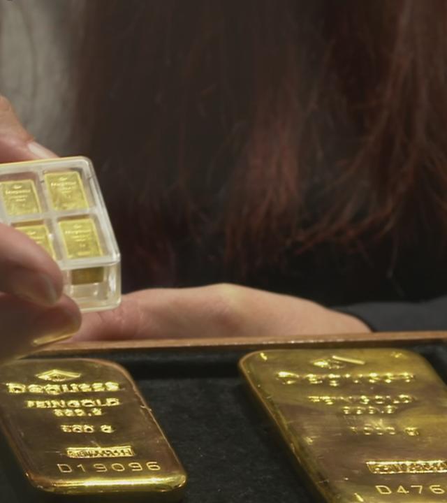Verschieden grpße Goldbarren liegen vor einer Kundin.