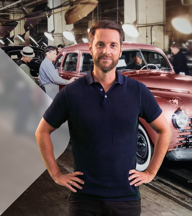Mirko Drotschmann vor Fließband, auf dem Autos gefertigt werden (Montage)