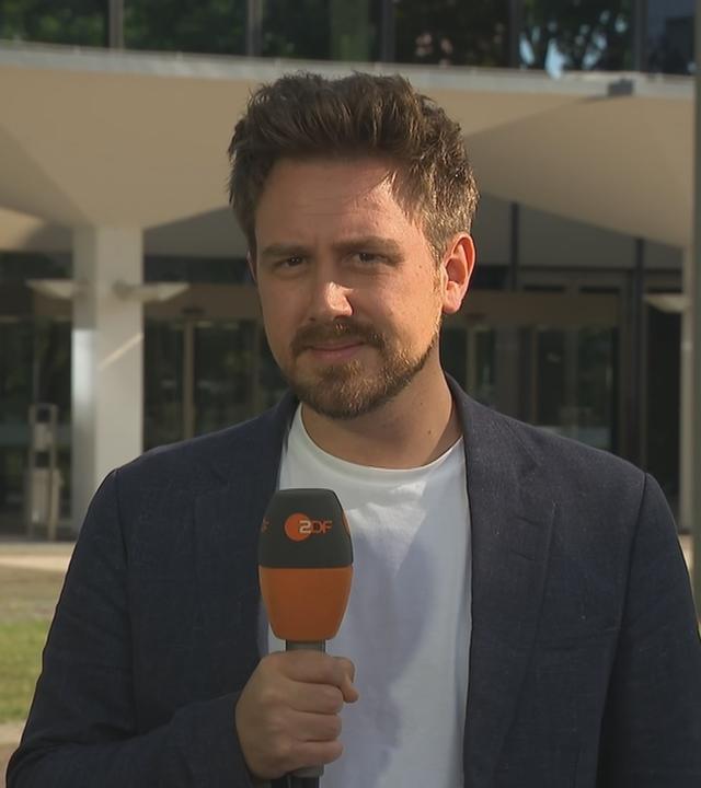 Jan Henrich blickt mit ZDF-Mikro in die Kamera