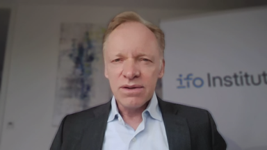 Ökonom Prof. Clemens Fuest Live zugeschaltet. Im Hintergrund ist ein Werbeaufsteller des ifo-Instituts zu sehen.