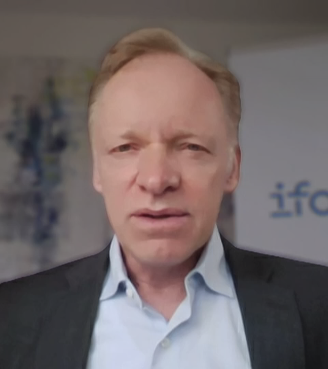 Ökonom Prof. Clemens Fuest Live zugeschaltet. Im Hintergrund ist ein Werbeaufsteller des ifo-Instituts zu sehen.
