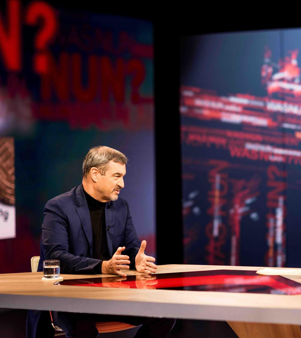 Markus Söder hinter einem Sprecherpult. Im Hintergrund eine blaue Leinwand. 