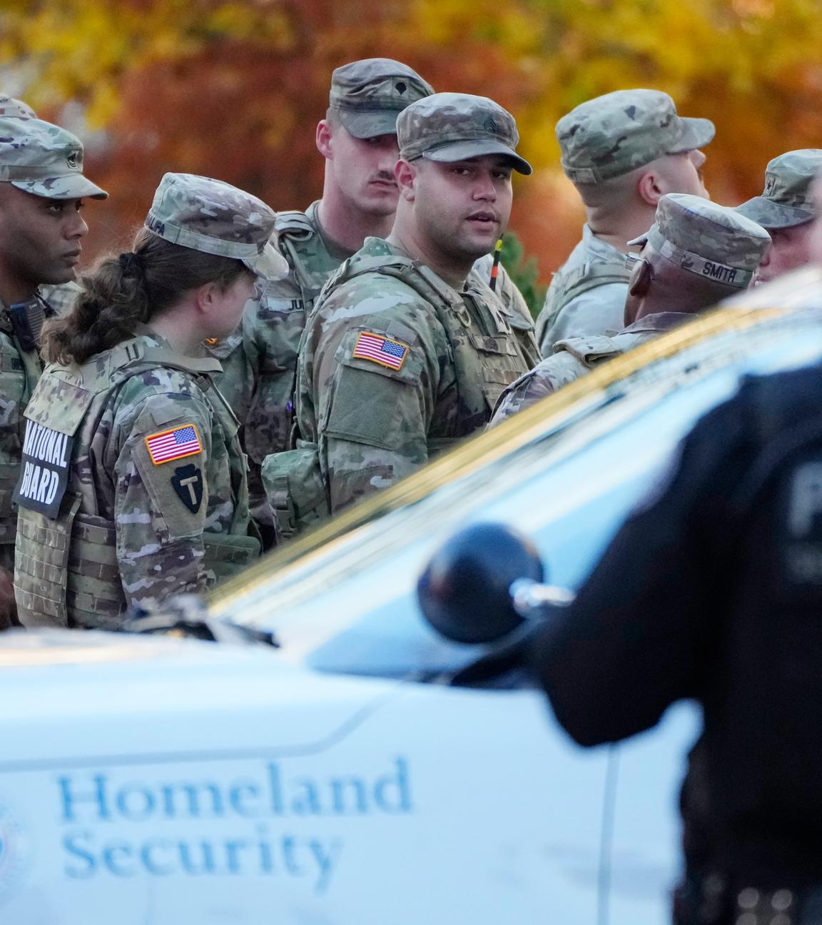 Mehrere Army Soldaten stehen vor einem Polizeiauto