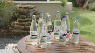 Viele Wasserflaschen unterschiedlicher Marken stehen auf einem Beistelltisch.