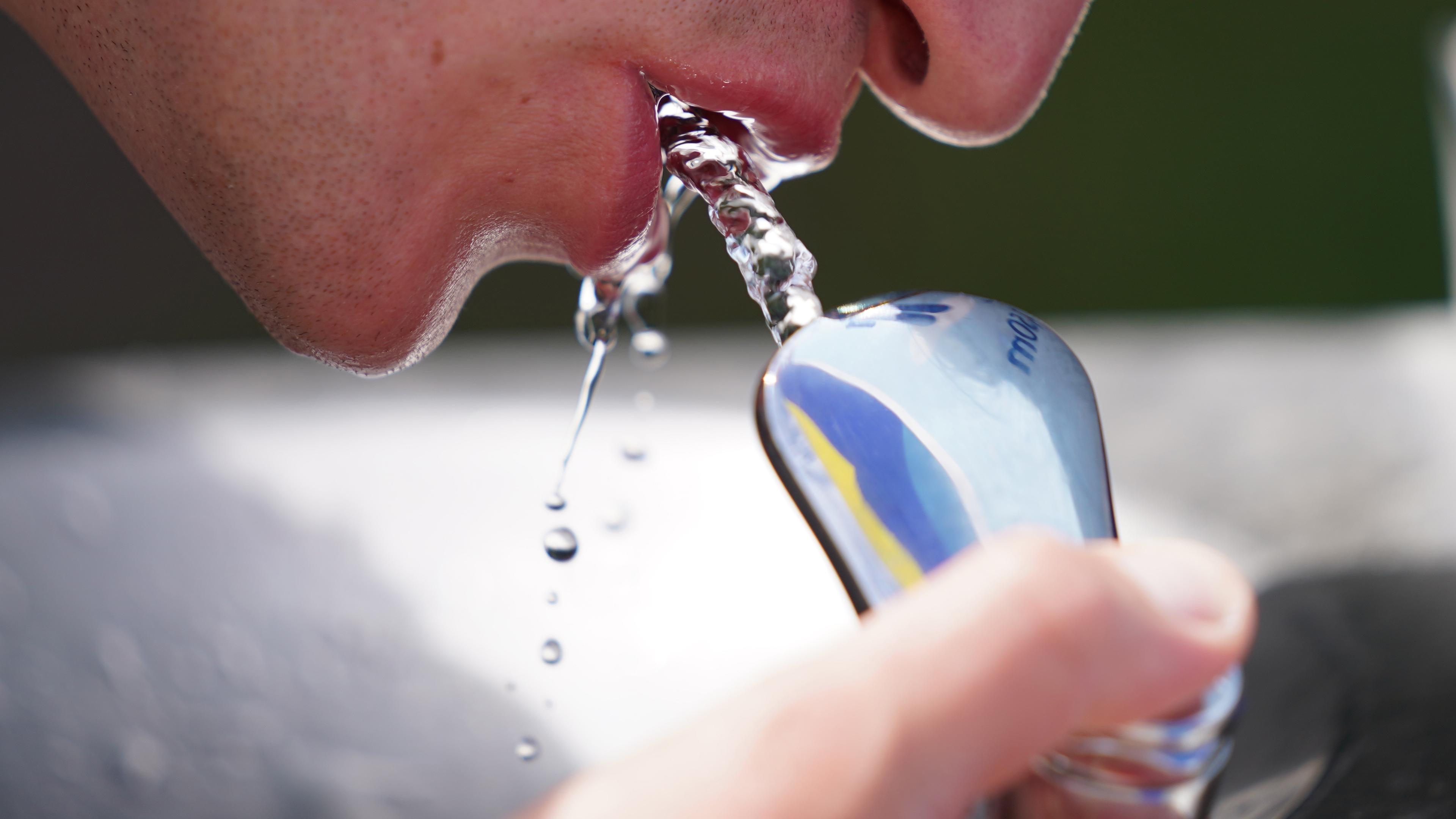Mann trinkt an einem öffentlichen Wasserspender