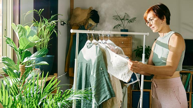 Eine Frau glättet Kleidung mit Wasserdampf