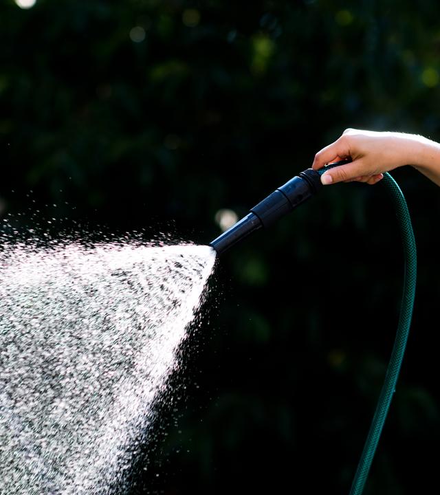 17.07.2018, niedersachsen, laatzen: eine frau steht mit einem gartenschlauch in einem garten und giesst pflanzen. niedersachsens wasserversorger reagieren gelassen auf die anhaltende hitze, den ausbleibenden regen und vor allen dem gesteigerten wasserverbrauch. 