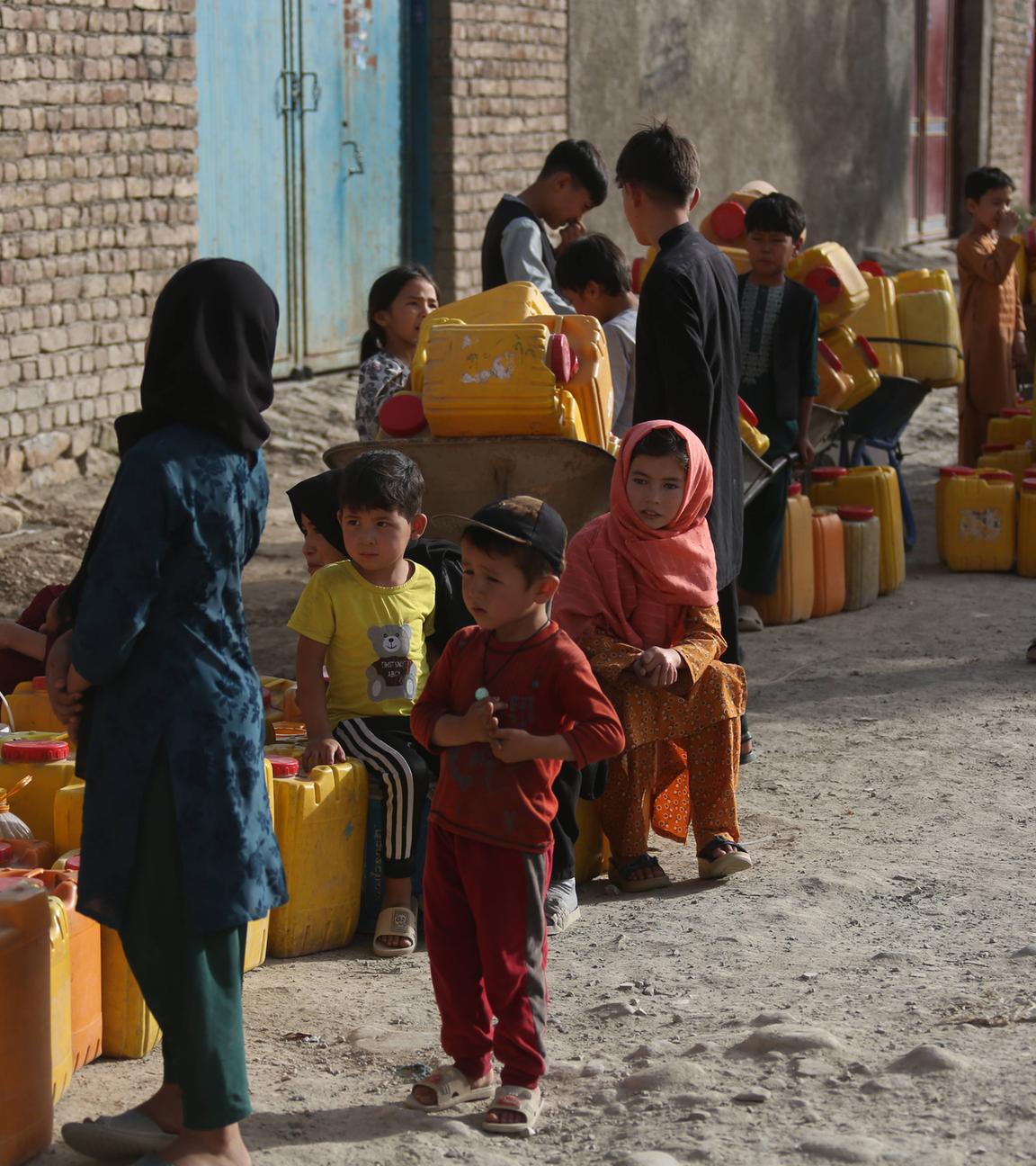 Kinder mit Plastikkanister warten an Brunnen in Kabul.