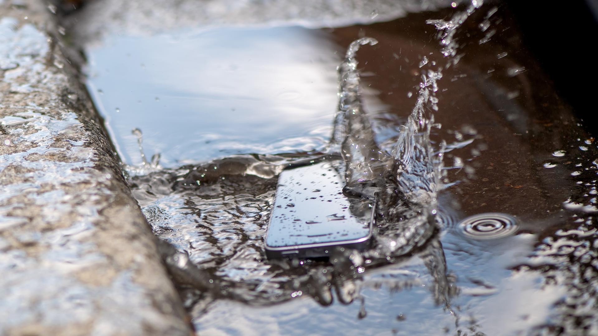 Ein Smartphone liegt in einer Pfütze.
