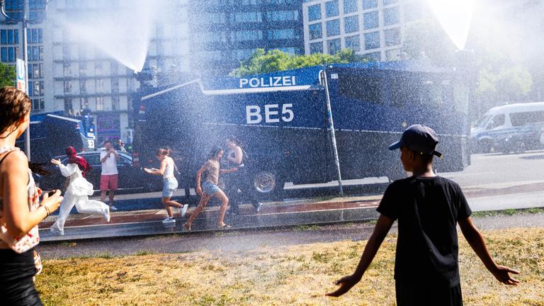 Ein Wasserwerfer der Polizei sprüht Wasser zur Abkühlung für Menschen am Potsdamer Platz.