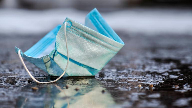 Weggeworfener Mundschutz liegt auf der Straße in München
