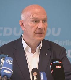 Kai Wegner ist während einer Konferenz zu sehen. Mehrere Mikrofone sind auf ihn gerichtet.