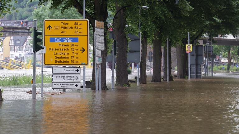 Ein Wegweiser steht zwischen zwei überfluteten Straßen