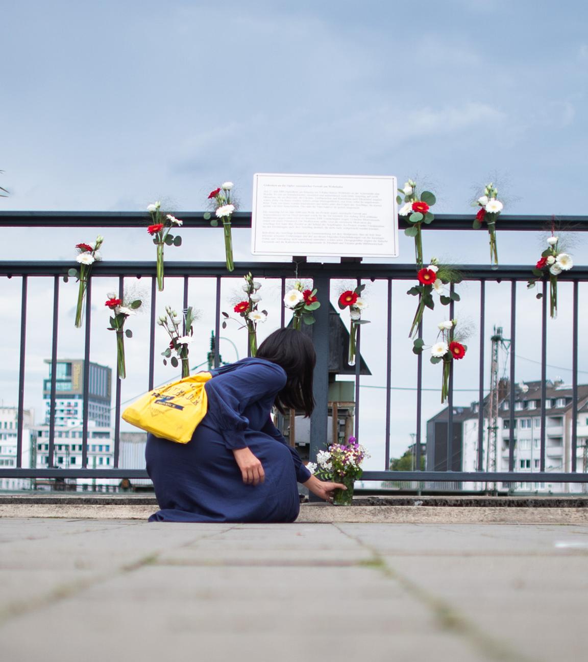 Eine Frau legt am Gedenkort am Bahnhof Wehrhahn Blumen nieder. (Archiv)