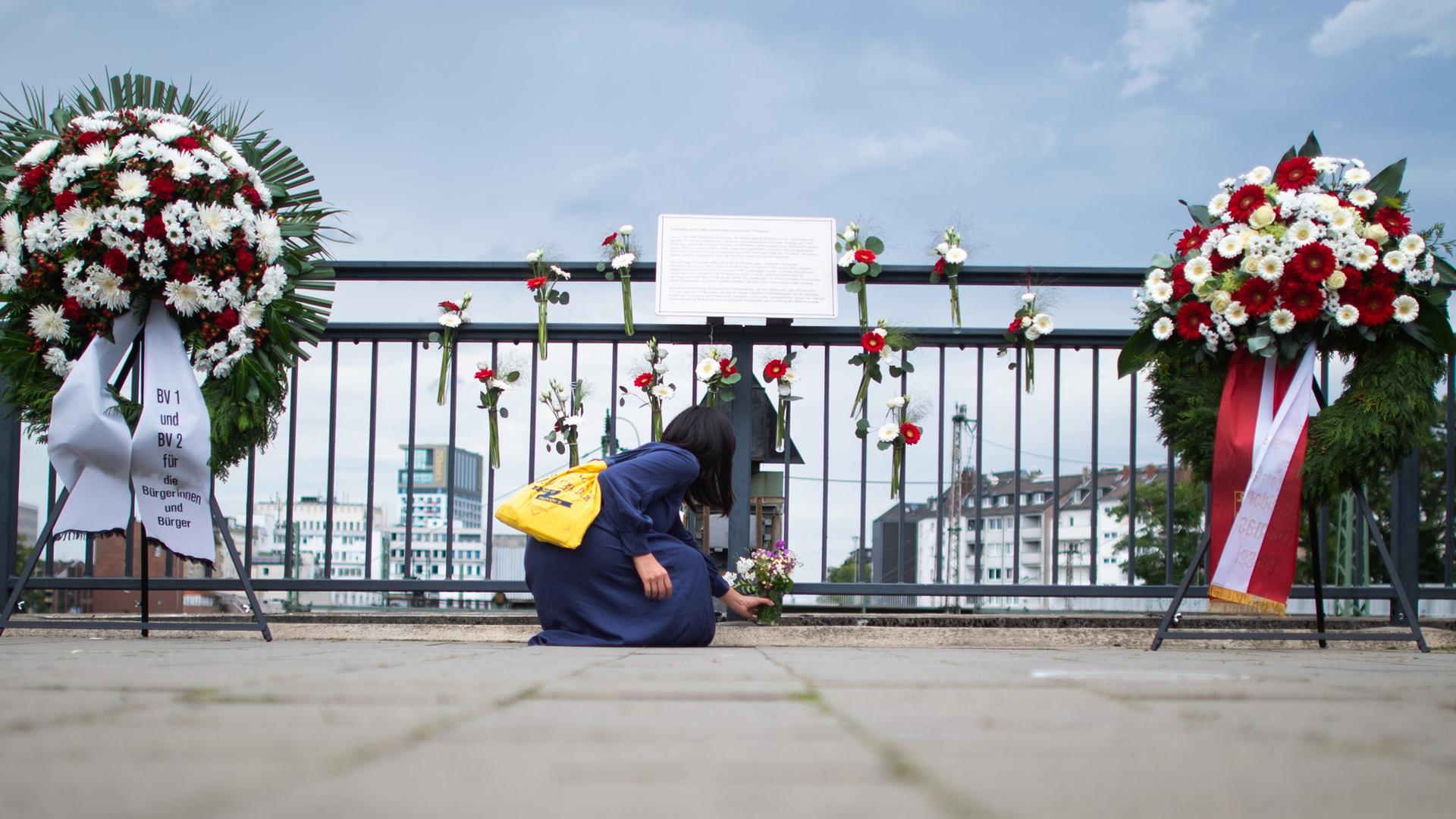Eine Frau legt am Gedenkort am Bahnhof Wehrhahn Blumen nieder. (Archiv)