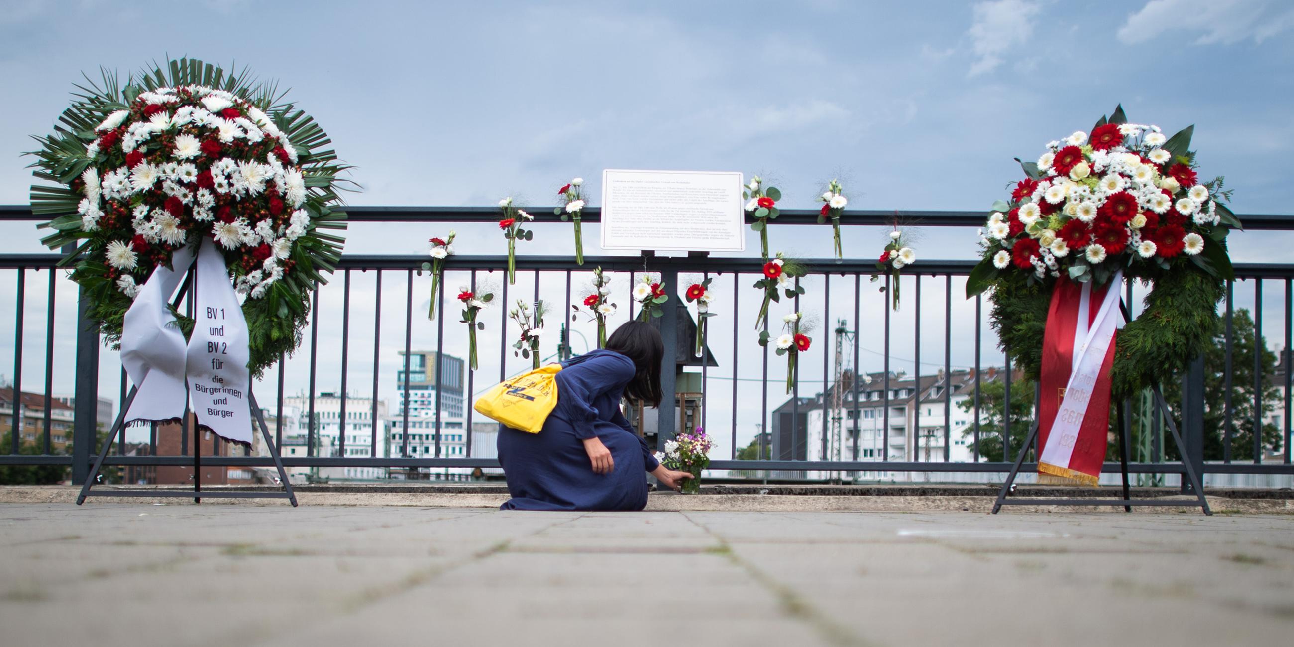 Eine Frau legt am Gedenkort am Bahnhof Wehrhahn Blumen nieder. (Archiv)