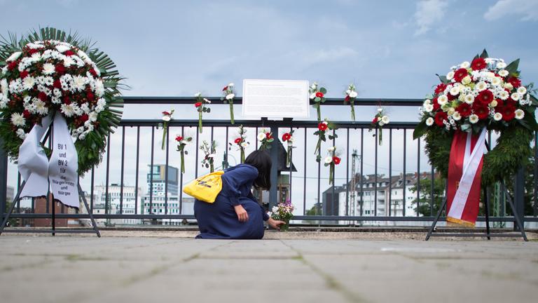 Eine Frau legt am Gedenkort am Bahnhof Wehrhahn Blumen nieder. (Archiv)
