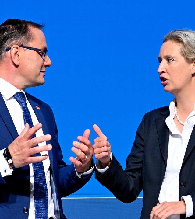 Tino Chrupala links & Alice Weidel rechts vor blauem Hintergrund auf dem AfD-Bundesparteitag, beide schauen sich an