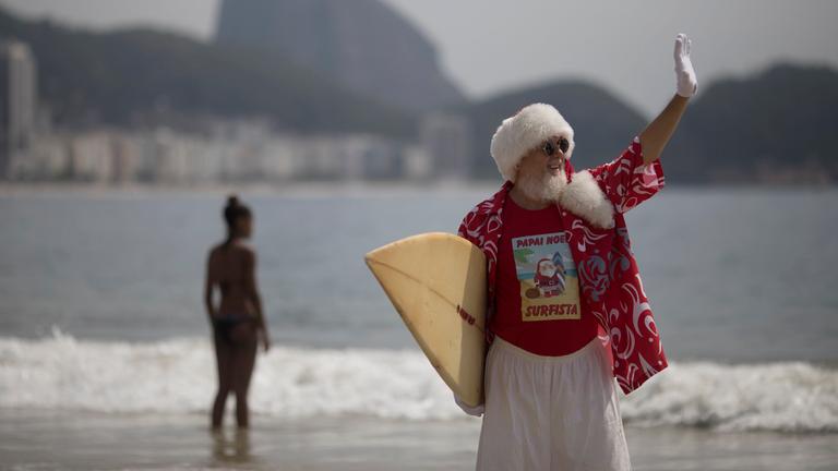 Ein Surfer im Weihnachtsmannverkleidung steht am 21.12.2017 am Strand von Rio de Janeiro (Brasilien)
