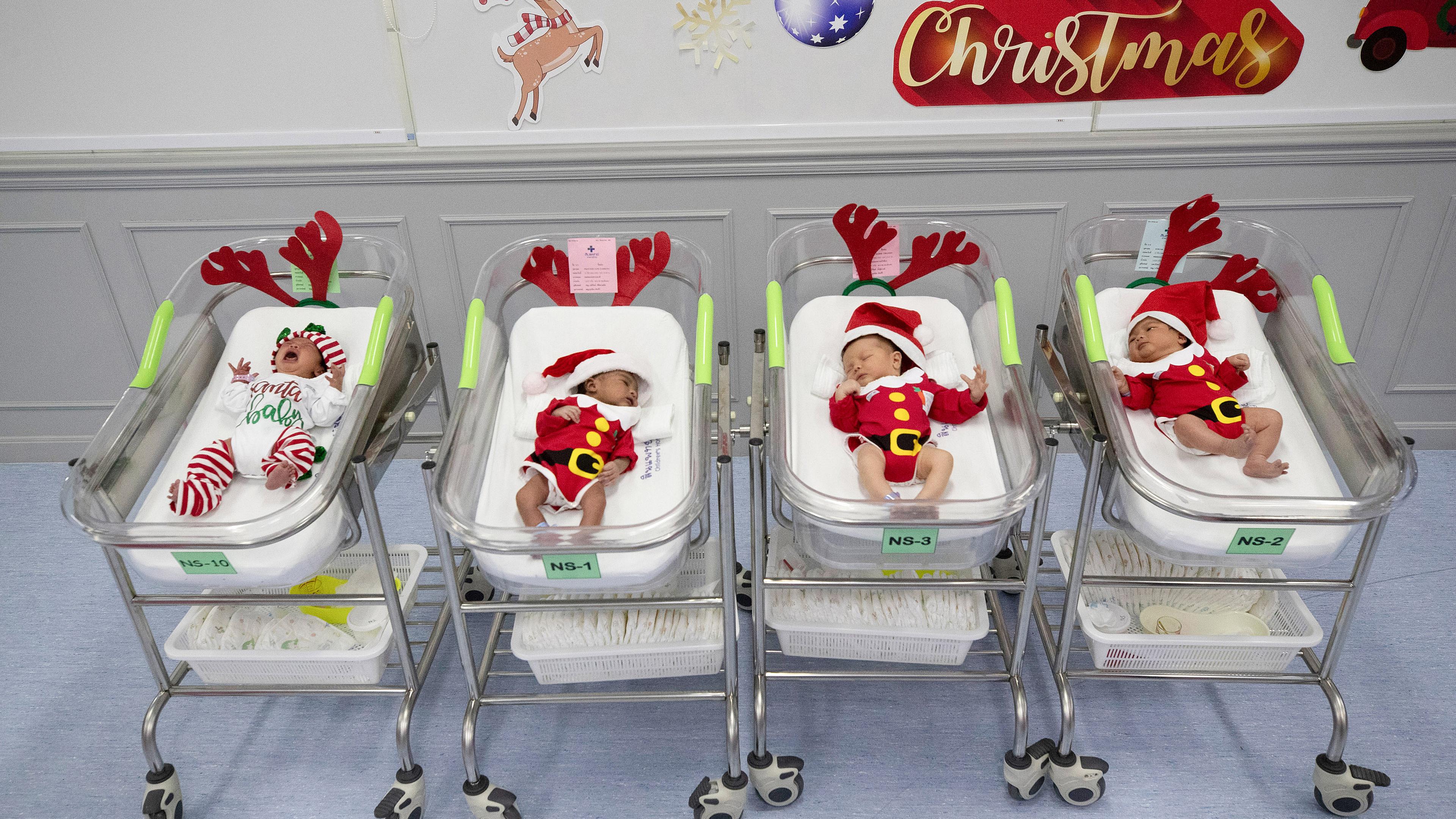 Neugeborene liegen am Heiligabend im Synphaet-Krankenhaus, Bangkok, Thailand, in Weihnachtsmannkostüme gekleidet
