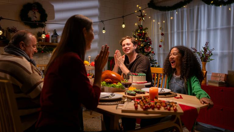 Familie sitzt an festlich gedecktem Tisch und unterhält sich angeregt.
