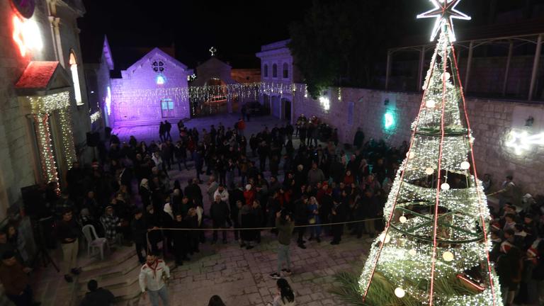 Bewohner versammeln sich am 20. Dezember 2025 in dem überwiegend christlichen Dorf Al-Qanayyah nordwestlich von Idlib in der Nähe eines beleuchteten Weihnachtsbaums, um sich auf die bevorstehenden Weihnachtsfeierlichkeiten vorzubereiten.