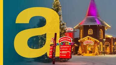 Großer Weihnachtsbaum und beleuchtetes Weihnachtshaus im "Weihnachtsdorf" in Finnland, daneben ein großes gelbes a