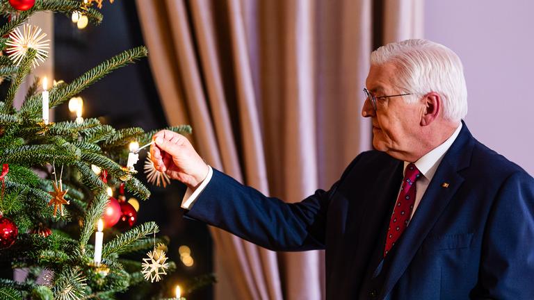 Bundespräsident Steinmeier zündet eine Kerze auf dem Weihnachtsbaum an.
