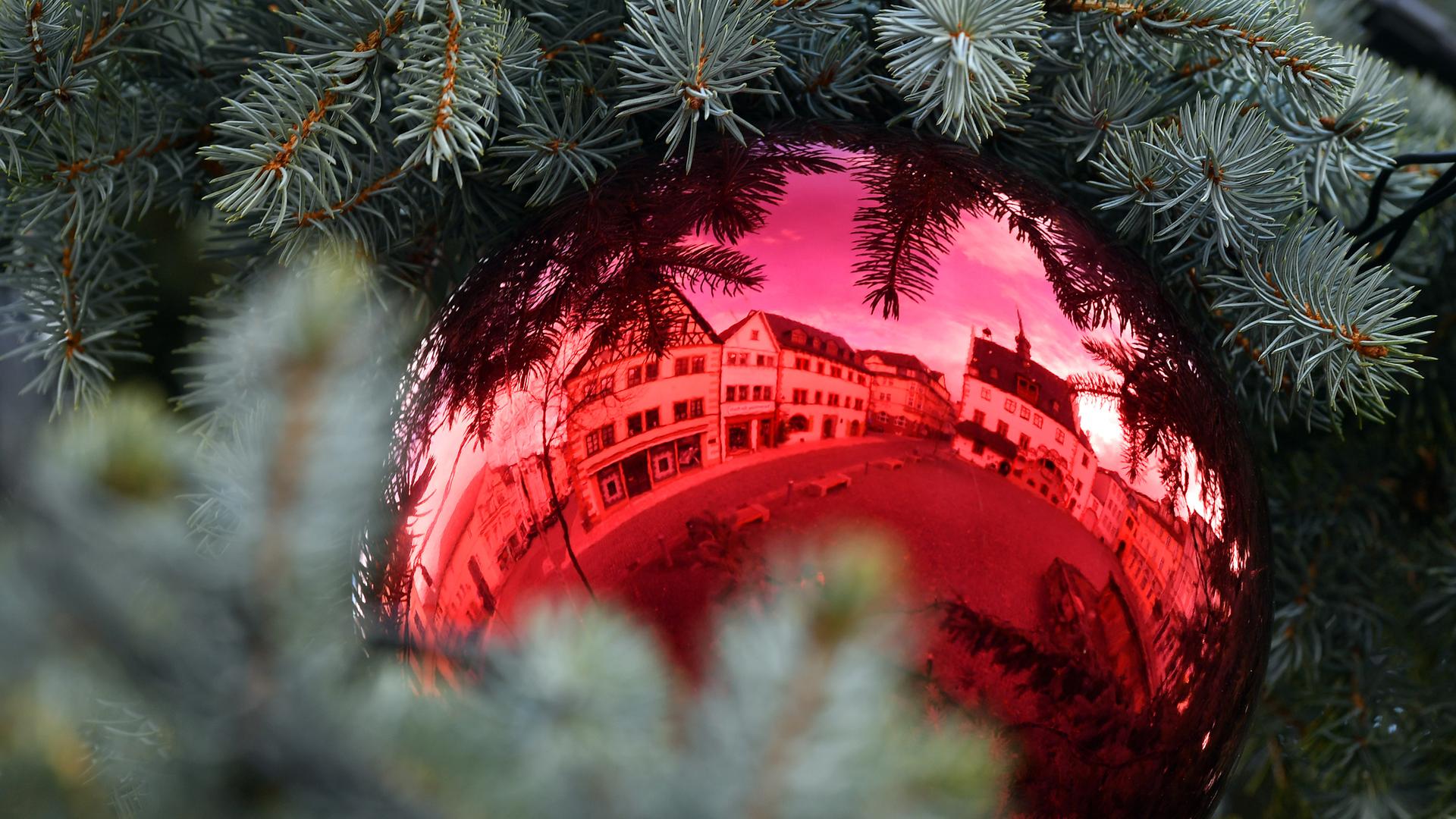 Rot leuchtet eine Kugel am Weihnachtsbaum
