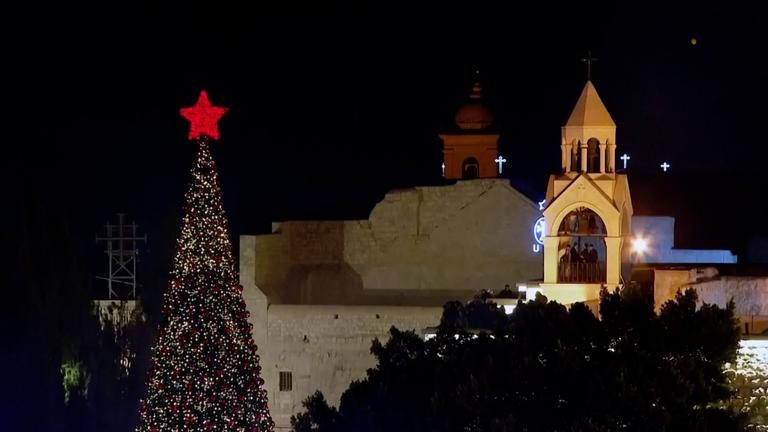 Ein großer Weihnachtsbaum in Bethlehem mit einem roten Stern an seiner Spitze leuchtet in der Nacht