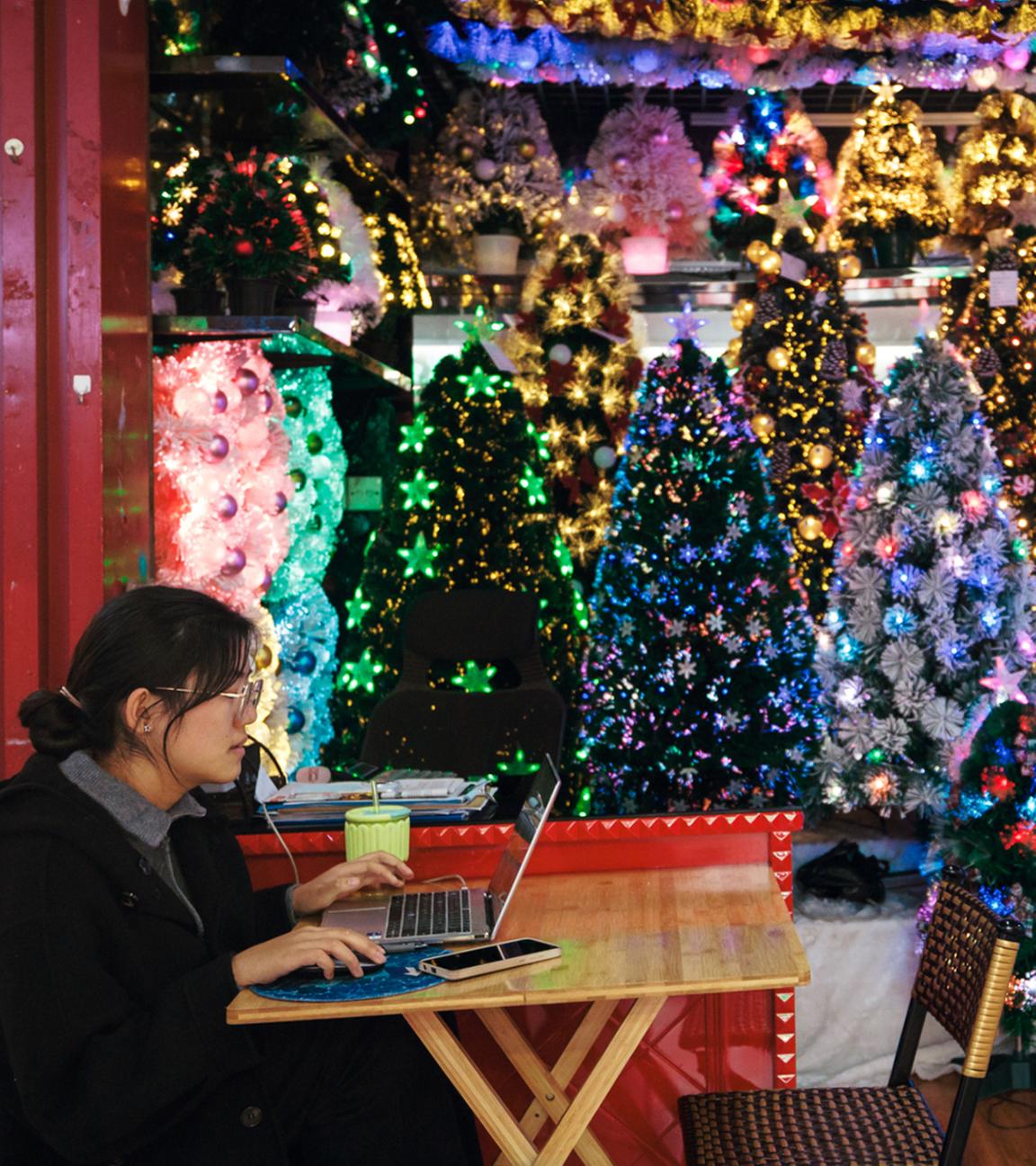 Eine Frau sitzt in ihrem Stand und verkauft Spielzeug, Weihnachts- und Neujahrsdekorationen auf dem Kunsthandwerksmarkt am 13. Dezember 2024 in Yiwu, China.