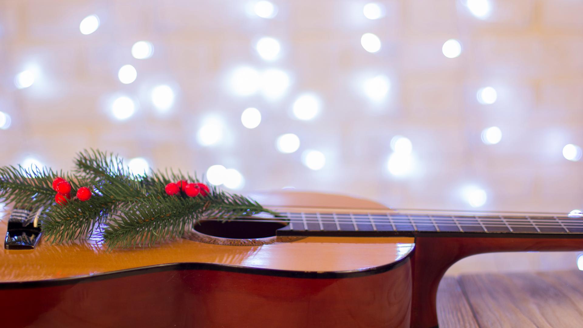 Eine mit einem Tannenzweig geschmückte Gitarre liegt auf dem Boden.