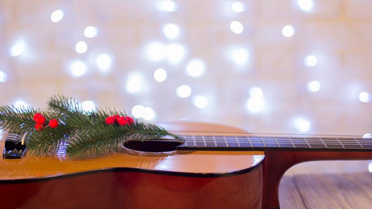 Eine mit einem Tannenzweig geschmückte Gitarre liegt auf dem Boden.