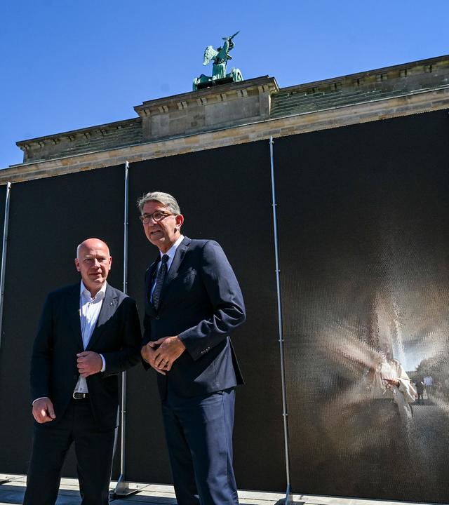 Kai Wegner (l, CDU), Regierender Bürgermeister von Berlin, und Wolfram Weimer (parteilos), Staatsminister für Kultur und Medien, besichtigen am Brandenburger Tor bei einem Pressetermin auf dem Platz des 18. März und eine Open-Air-Ausstellung Mauerblicke. 