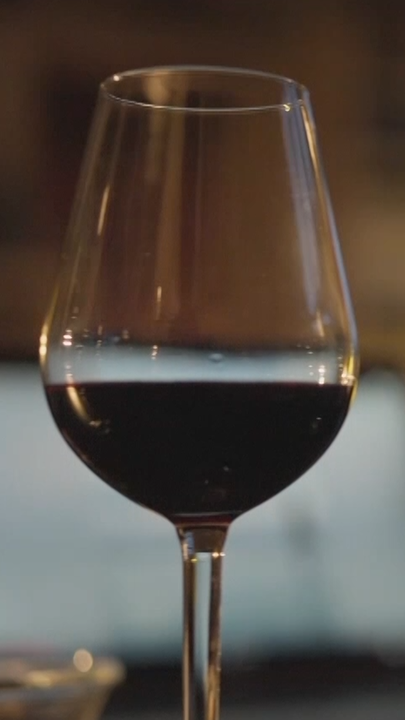 Zwei Weingläser mit Rotwein gefüllt stehen auf einem Tisch.