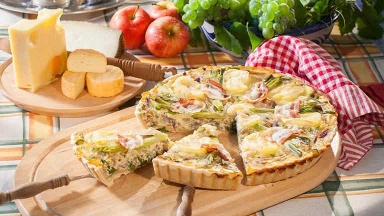 Weinkäse-Zwiebelkuchen auf einem Holzbrett angerichtet