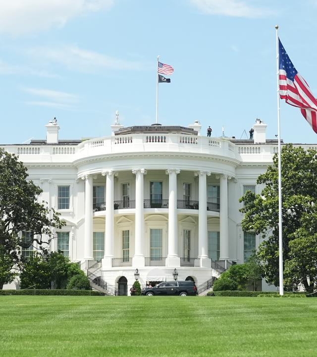 Weißes Haus in Washington mit USA-Flagge im Vordergrund
