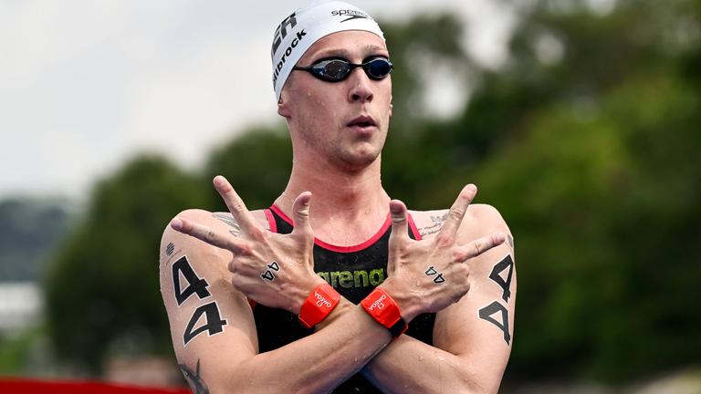 Florian Wellbrock kreuzt die Arme und streckt mit beiden Händen drei Finger