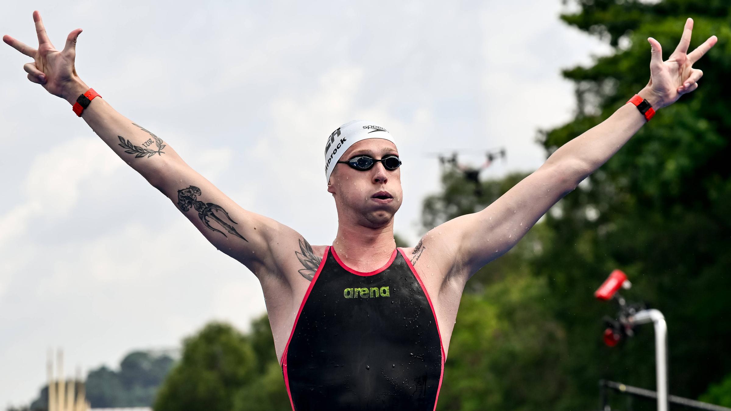 Florian Wellbrock zeigt bei der Schwimm-WM in Singapur nach seinem dritten Einzelsieg mit den Fingern beider Hände eine 3.
