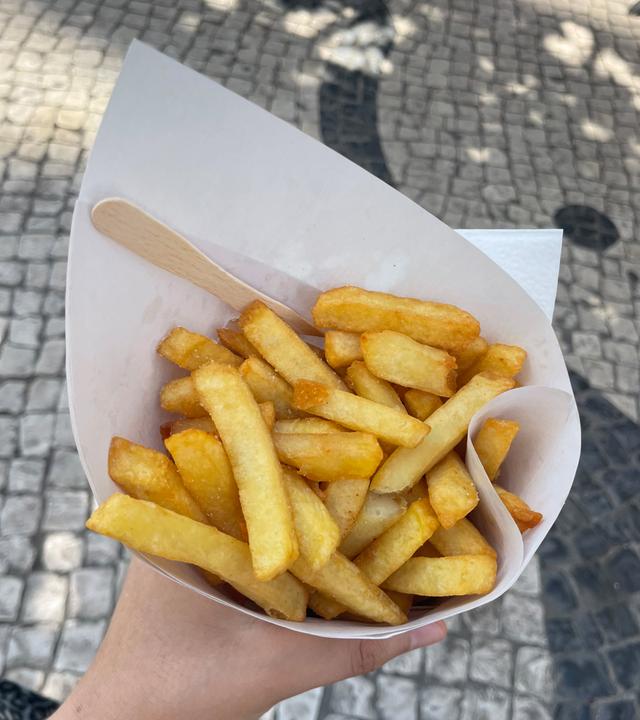 Belgische Pommes Frites in einer Papiertüte mit Pommesgabel.