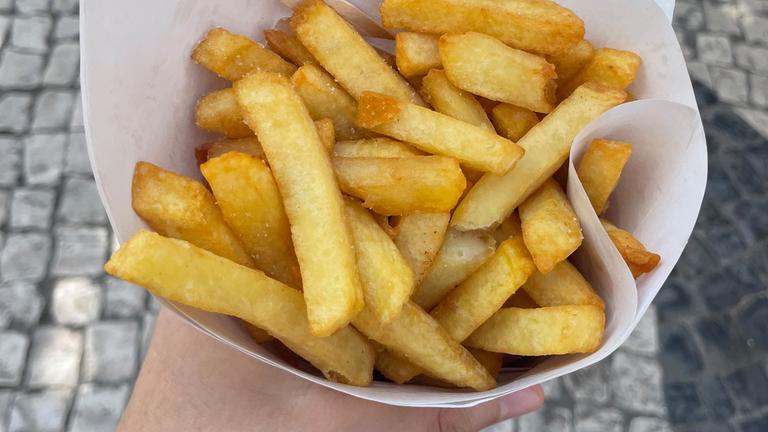 Belgische Pommes Frites in einer Papiertüte mit Pommesgabel.