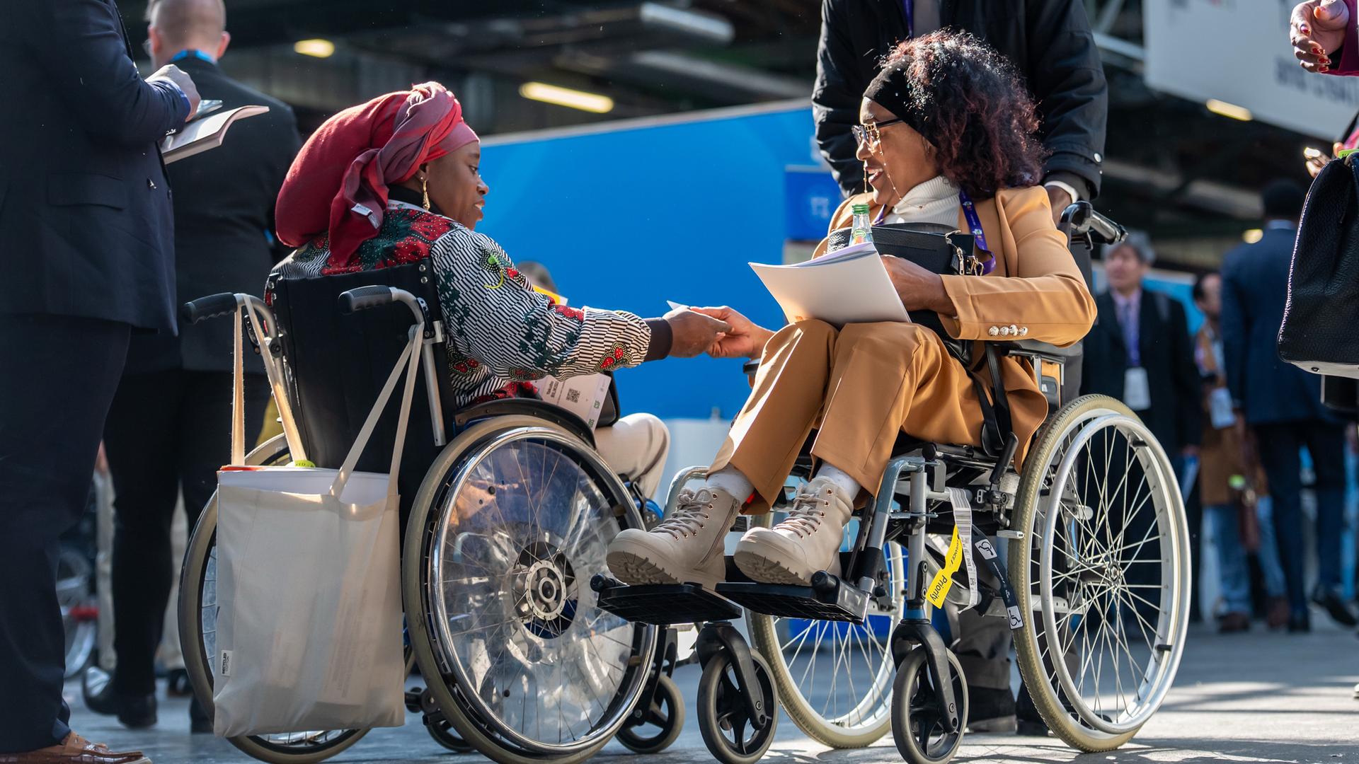 Besucherinnen im Rollstuhl sind auf dem Weltgipfel für Menschen mit Behinderungen unterwegs.